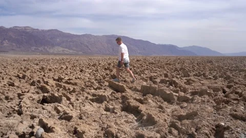 A man walks on the rocks at the Devil's Golf Course in Death Valley, USA Stock Footage 153977448