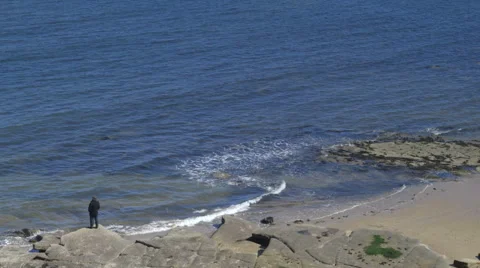 A man walks on a rocky beach. Stock Footage 67826388