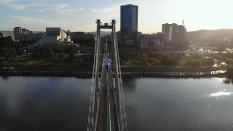 A man walks on a rope stretched between the supports of the bridge at high Stock Footage 113066988