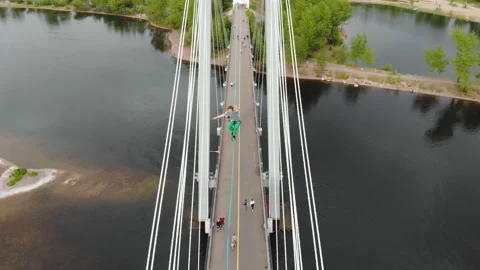A man walks on a rope stretched between the supports of the bridge at high Stockbeeldmateriaal 113144225