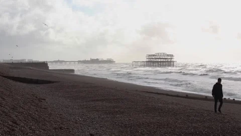 Man walks by the Sea with Old Pier and Palace Pier in the Background Vidéo 287442653