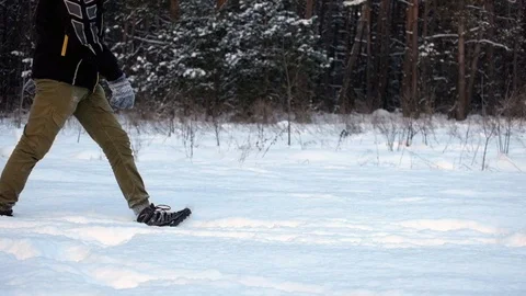 Man walks in the snow, slips and falls smoothly moving into slow motion Stock Footage 101310513