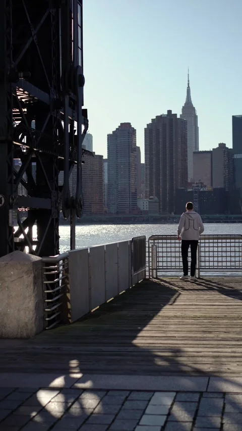 Man walks by the soothing waters while enjoying a stunning NYC skyline view Vidéo 291636689