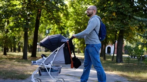 Man walks with a stroller in the park. Caring father for a walk with a child Stock Footage 118690631