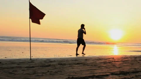 A Man Walks on th Beach at Sunset Speaking on a Cell Phone Stock Footage 39908883