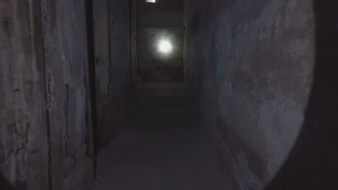 A man walks through a dark old abandoned basement and shines a flashlight Stock Footage 168226644
