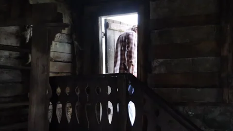A man walks through a door from a dark room into the street Video stock 277019695