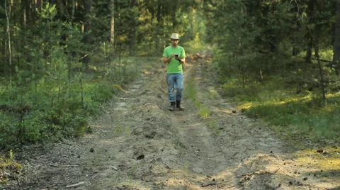 A man walks through the forest with the phone and looks at the navigation Stock Footage 65016734