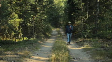 A man walks through the forest with the phone and looks at the navigation Stock Footage 65018889