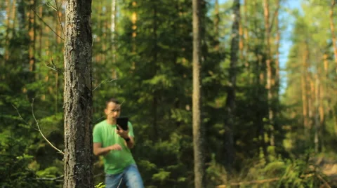 A man walks through the forest with a tablet PC and looking at the navigation Stock Footage 65022557