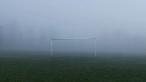 Man walks through goal posts on misty atmospheric sports field wide shot 스톡 동영상 78008310