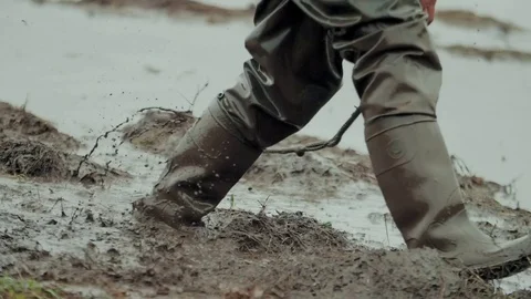 Man walks through the mud in rubber boots Vidéo 98596132