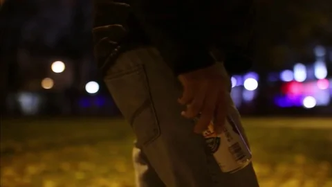 A man walks through the park with a can of beer in his hand Stock Footage 83136560
