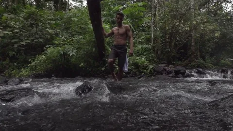 Man Walks Through River in The Middle of a Jungle Stock Footage 87723459