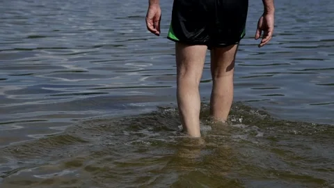 A man walks through the shallow water of a mountain lake. Unity with nature Video stock 158170348