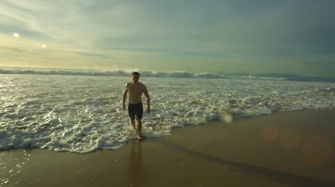 Man walks with the tide of a wave on beach Stockbeeldmateriaal 60712062