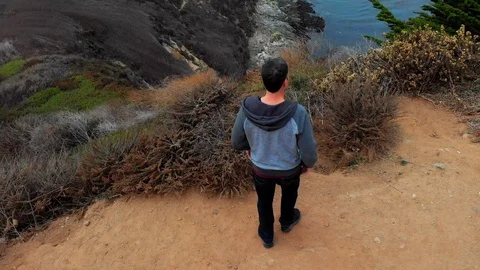 Man Walks Toward Cliff Edge Looking Down Stock Footage 101446122