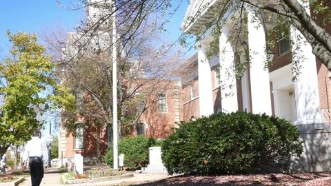 Man walks up to a town hall in small american town during daytime Stock Footage
