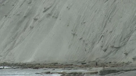 Man walks under cliffs by sea Stock Footage 22338372