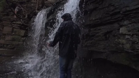 Man Walks Under Rushing Waterfall Stock Footage 79736565