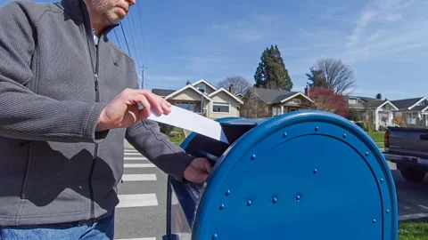 Man walks up to a USPS mailbox to mail a letter Stock Footage 275302355