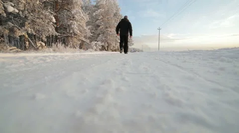 A man walks on a winter snowy road. Video stock 59772987