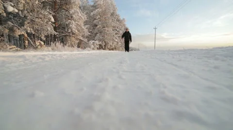 A man walks on a winter snowy road. Video stock 59773167