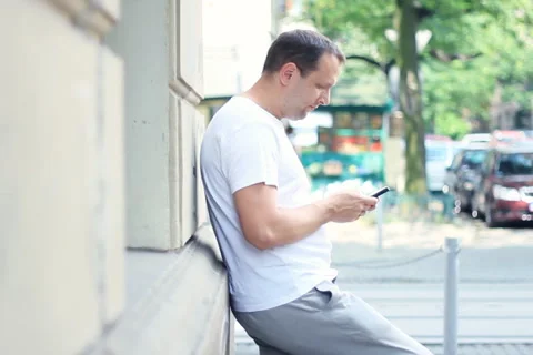 Man by the wall sending sms message in the city NTSC Stock Footage 6808252