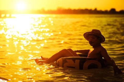 A man ware hat and he is on swim tube in the water. Stock Photos