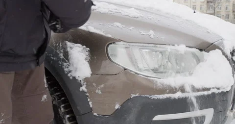 Man in warm clothes cleans his car from snow Stock Footage 169585185