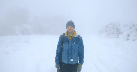 A man in a warm denim jacket walks along a deserted snowy road Stock Footage 149078046