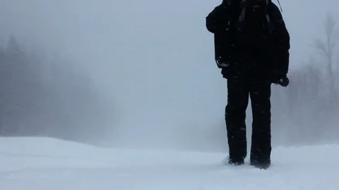 Man in warm down jacket goes into blizzard, view from back, strong wind, forest Stock Footage 128978098