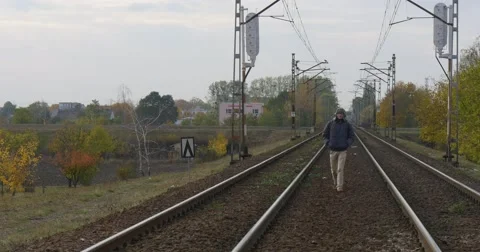 Man in Warm Ushanka Hat Jacket And Earphones is Walking Toward by Railroad Stock Footage 56961920