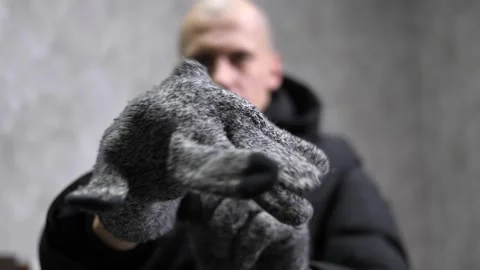  man in a warm winter jacket puts knitted gray gloves Stock Footage 260639343