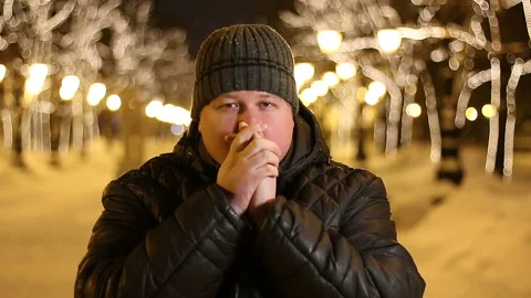 Man warming up and heating hands near mouth outdoors on a winter night Stock Footage 104819361