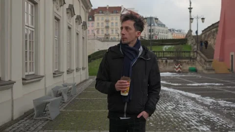 Man warming up with coffee on a thoughtful winter walk in a historic city Stock Footage 311192654