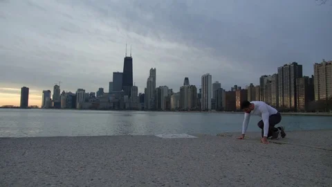 Man is warming up on the ebankment. Athlete training outdoors. Downtown with Stock-Footage 82644313