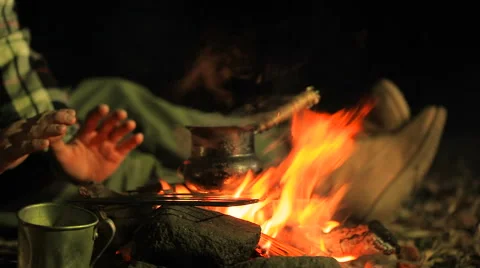 Man warming hands and waiting for coffee (tea) near the campfire. Stock Footage 68946217
