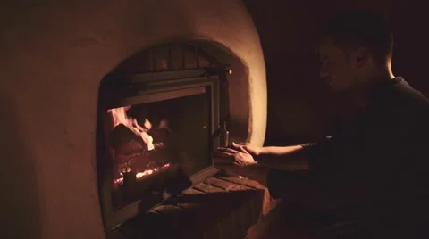 Man warming Hands in front of Burning Fireplace, 4K. Stock-Footage 66730731