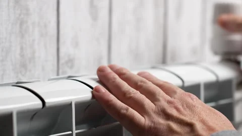 A man warming hands with heating radiator at home, close-up Stock Footage 288011978