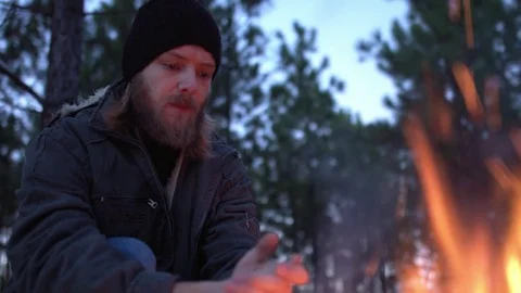 Man warming his hand by the fire in a forest. Stock Footage 76845172