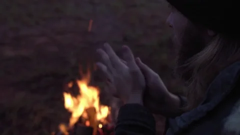 Man warming his hand by the fire in a forest. Stock Footage 76845446