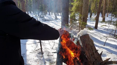 The man is warming his hands around a fire in the forest. Stock Footage 105103745