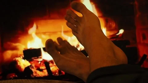 A man warms bare feet by the fireplace. Stock Footage 100703273