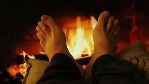 A man warms bare feet by the fireplace. Stock Footage 100741611