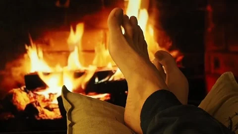 A man warms bare feet by the fireplace. Stock Footage 100741613