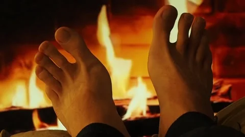 A man warms bare feet by the fireplace. Stock Footage 100741634