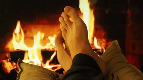 A man warms bare feet by the fireplace. Stock Footage 100741636