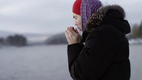 Man warms hands near winter lake Stock Footage 70806461