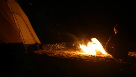 A man warms himself by the fire at night on the shore Stock Footage 115992365